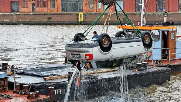 Weißer Audi hängt tropfend kopfüber am Kran